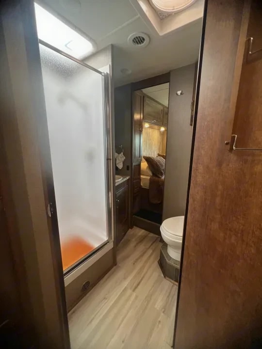 Bathroom doorway showing frosted shower door and toilet beyond