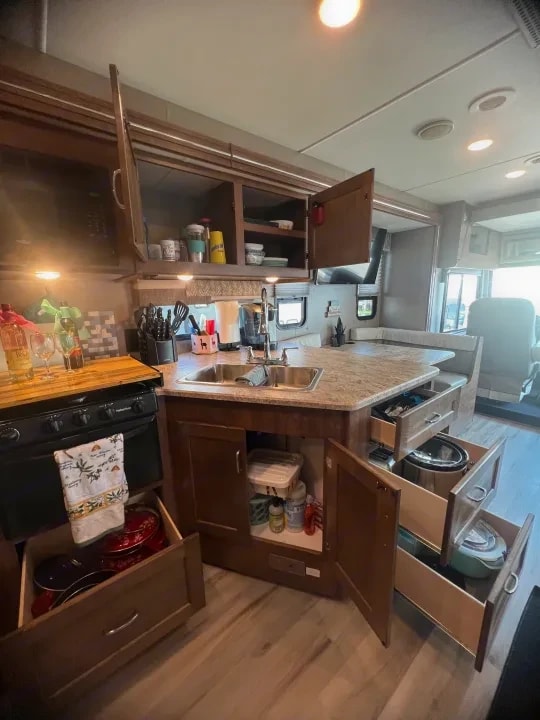 Kitchen island with sink, open overhead cabinet, and pull-out storage drawers