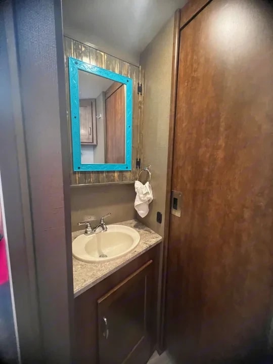Bathroom vanity with oval sink and turquoise-framed mirror