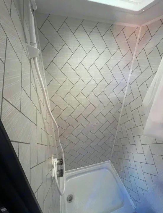 Herringbone-tiled shower stall with handheld showerhead