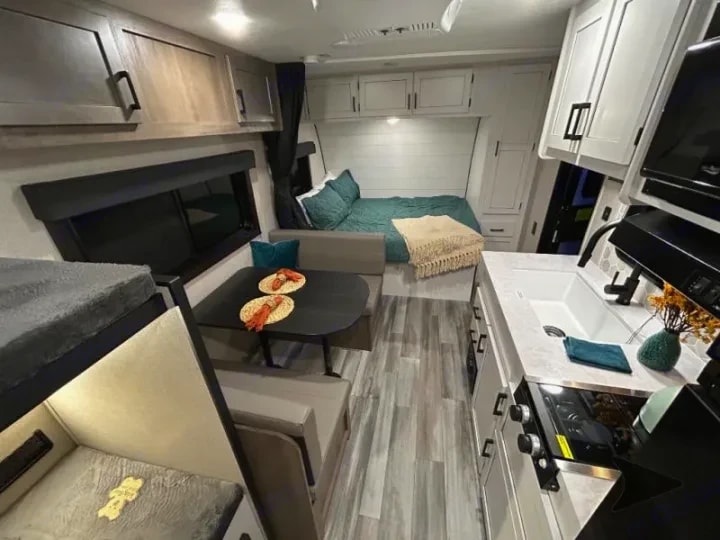 View across the dinette and lounge toward the bed at the front of the trailer