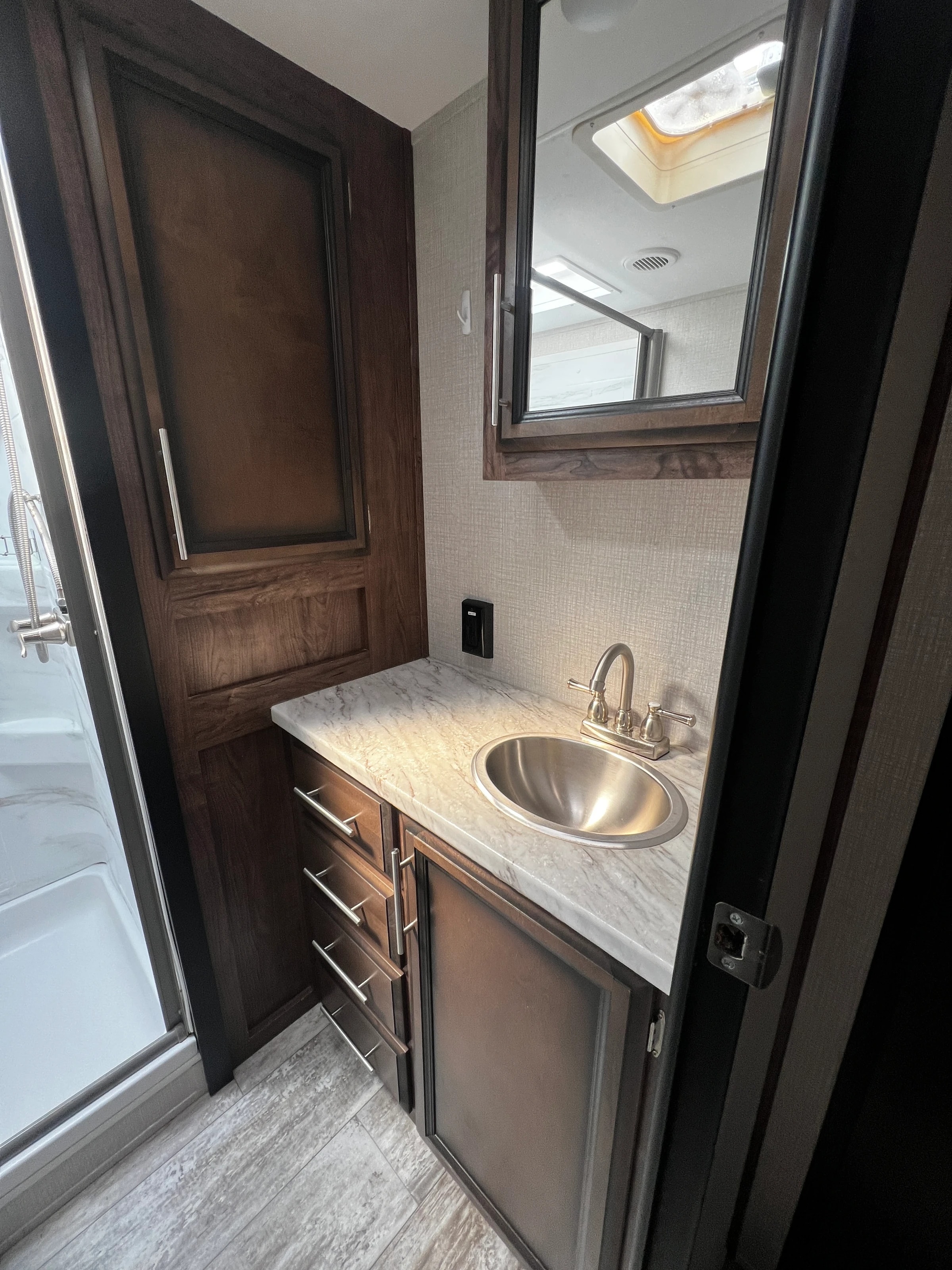 Bathroom vanity with wood cabinet, stone counter, and mirrored medicine cabinet