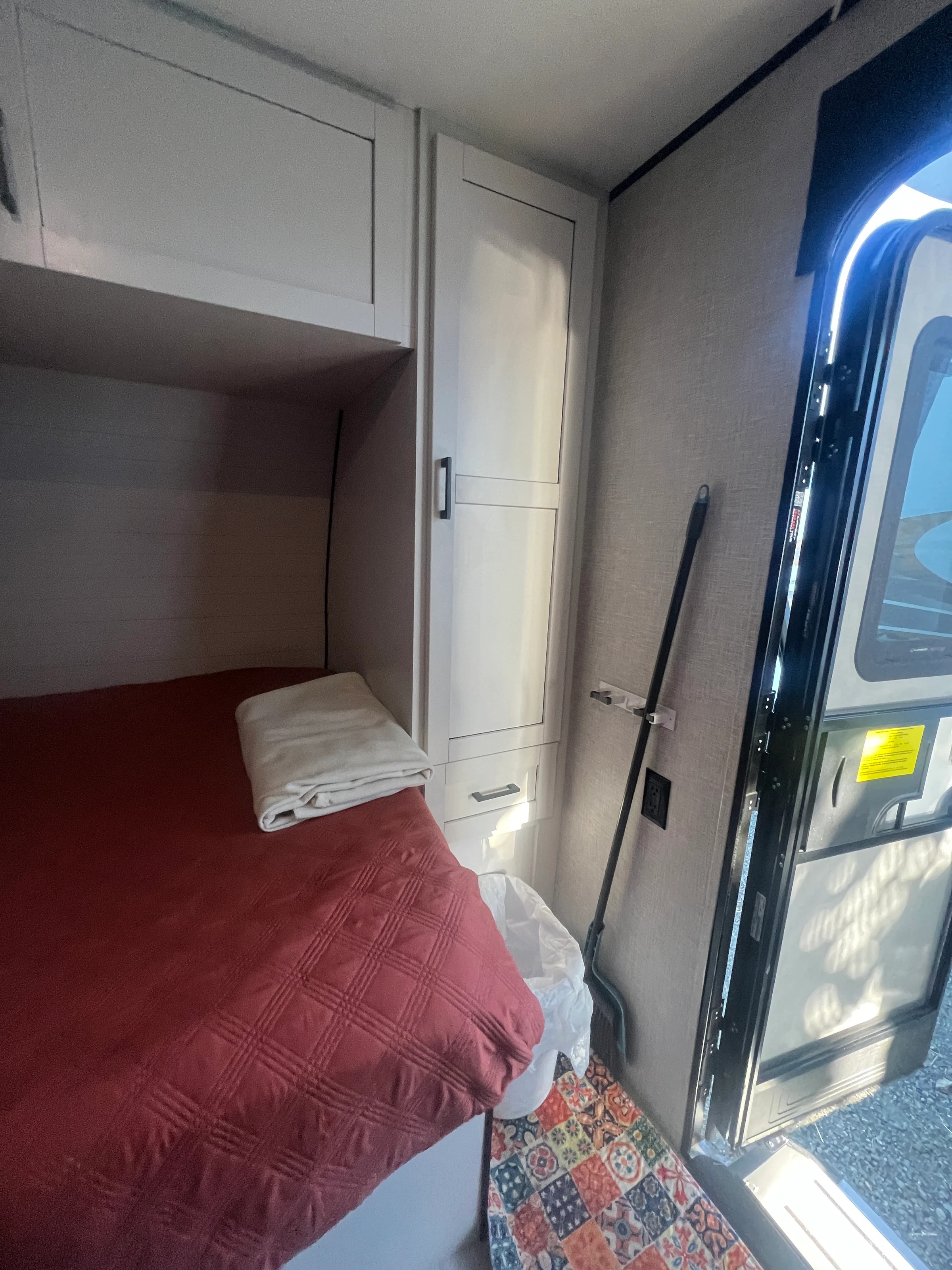 Bunk beds made up with red quilts beside the entry door