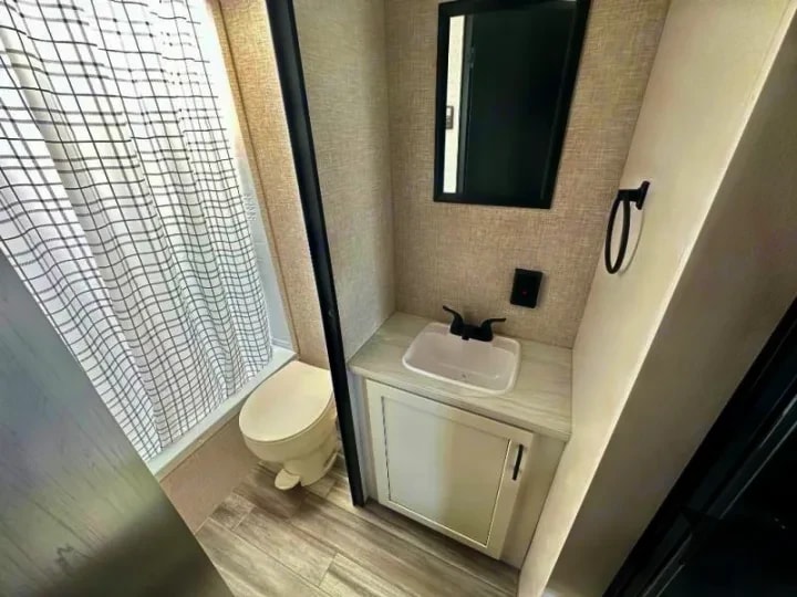 Bathroom with toilet, shower curtain, and vanity sink
