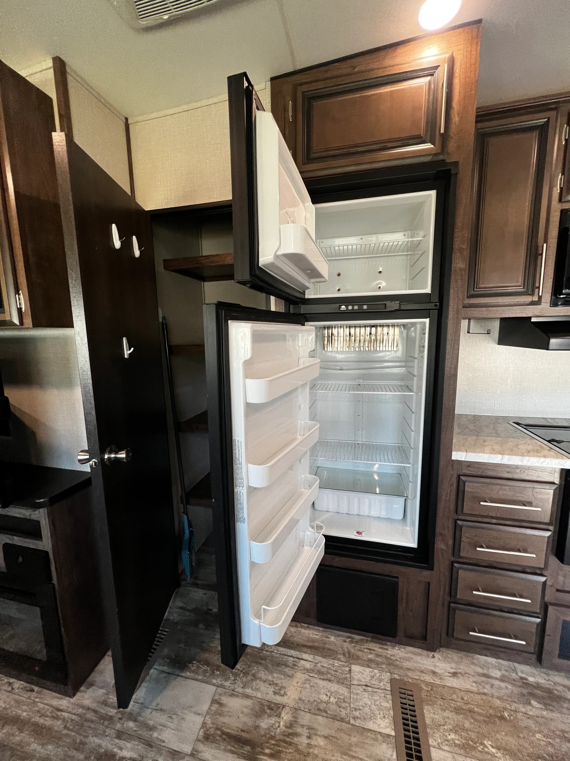Open refrigerator and adjacent pantry closet with wood shelving in the kitchen