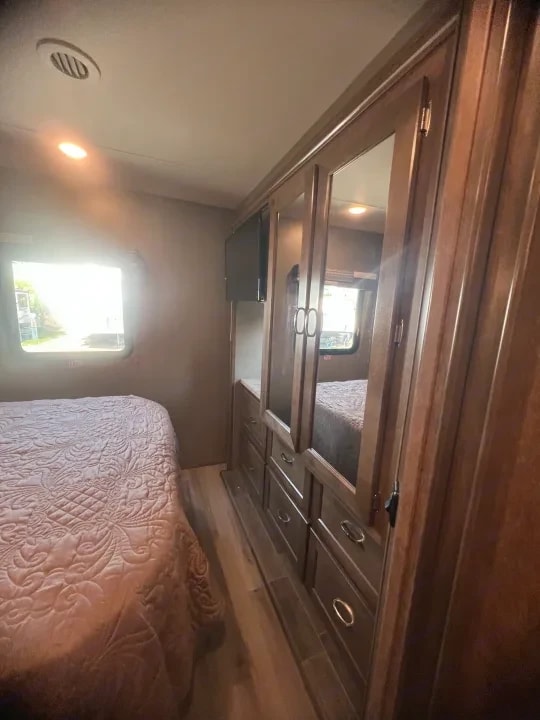 Bedroom corner showing wardrobe cabinet with mirrored doors beside the bed