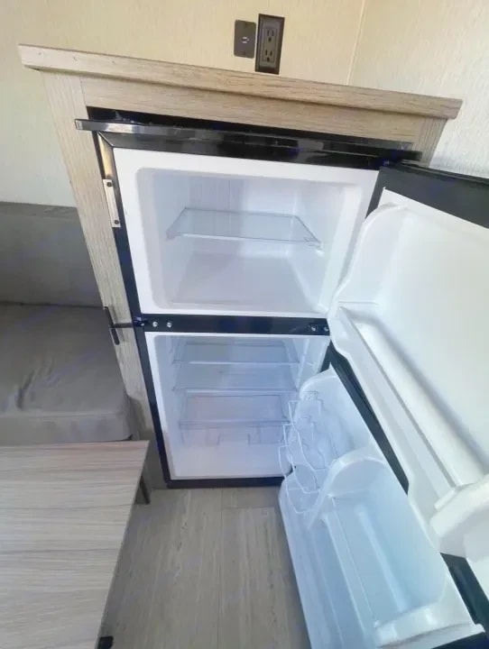 Open two-door refrigerator with empty shelves and door bins