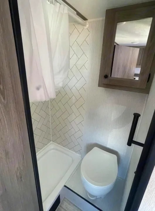 Bathroom with tiled shower stall, toilet, and mirrored medicine cabinet