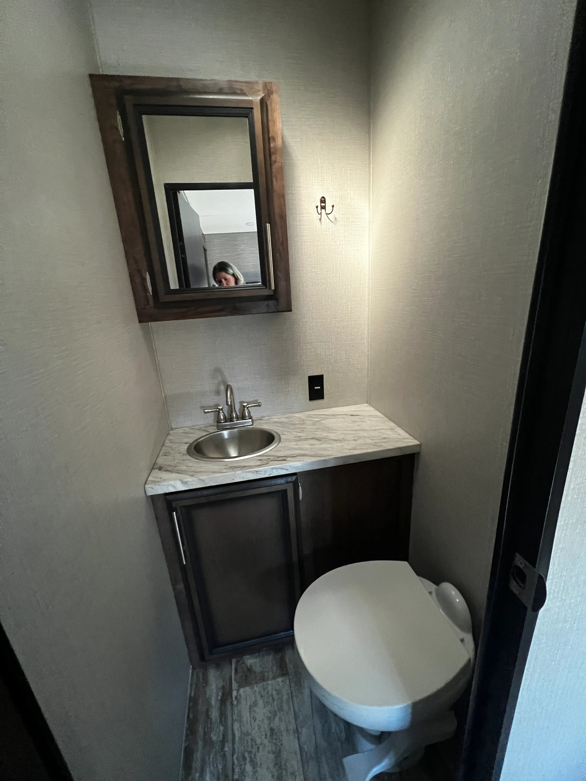 Half bath with pedestal-style sink, wood vanity, mirror, and toilet