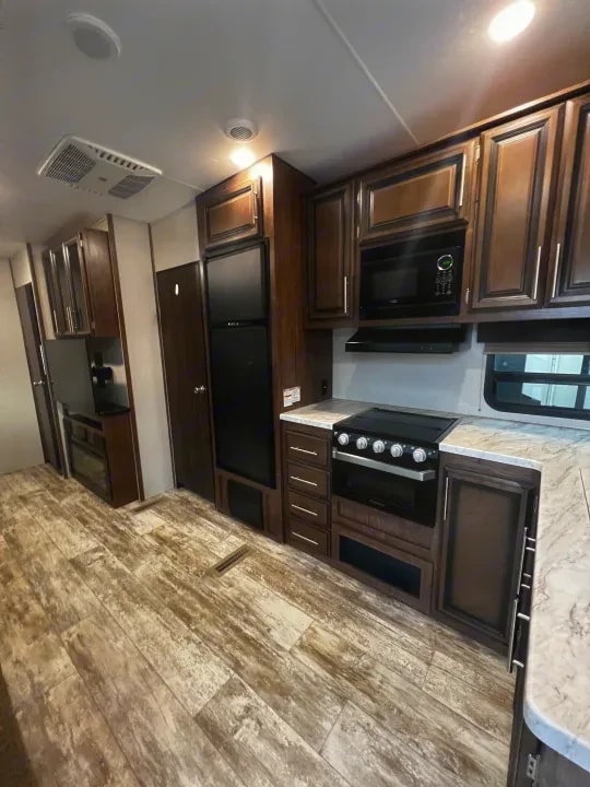 Kitchen view showing range, microwave, and cabinetry from the hallway