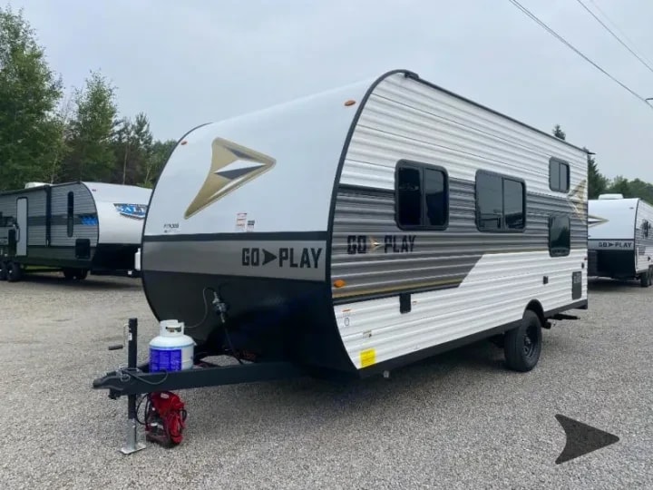 Exterior three-quarter view of the trailer parked on gravel among other RVs