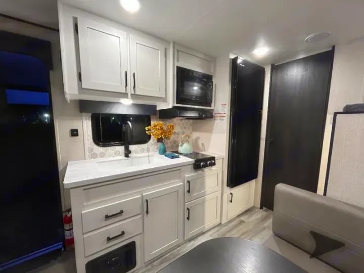 Kitchen counter with sink, stovetop, and overhead cabinets