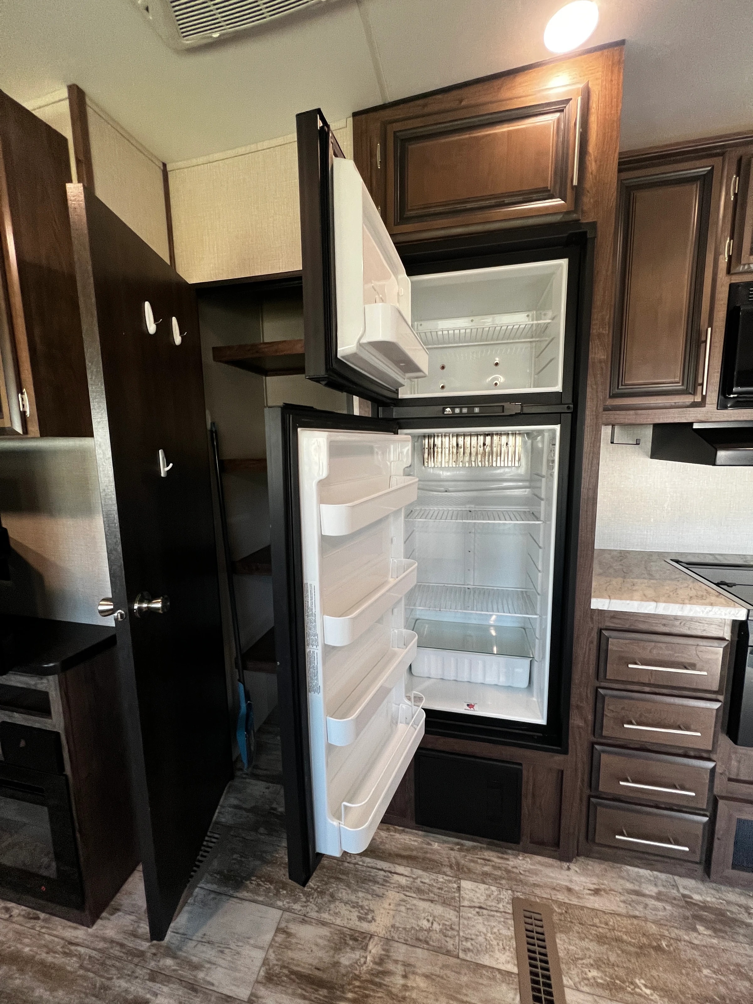 Refrigerator and freezer standing open beside the pantry