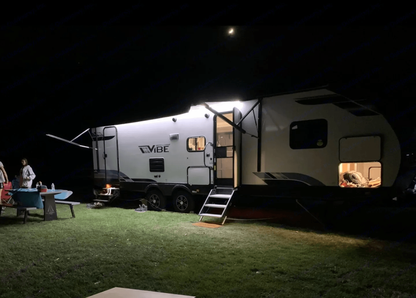 Camper lit up under its awning after dark