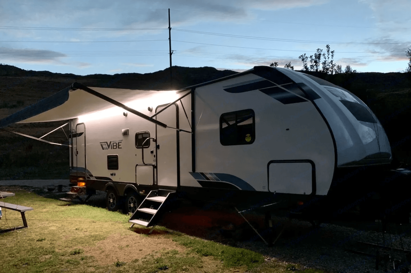 Travel trailer with its awning out at dusk